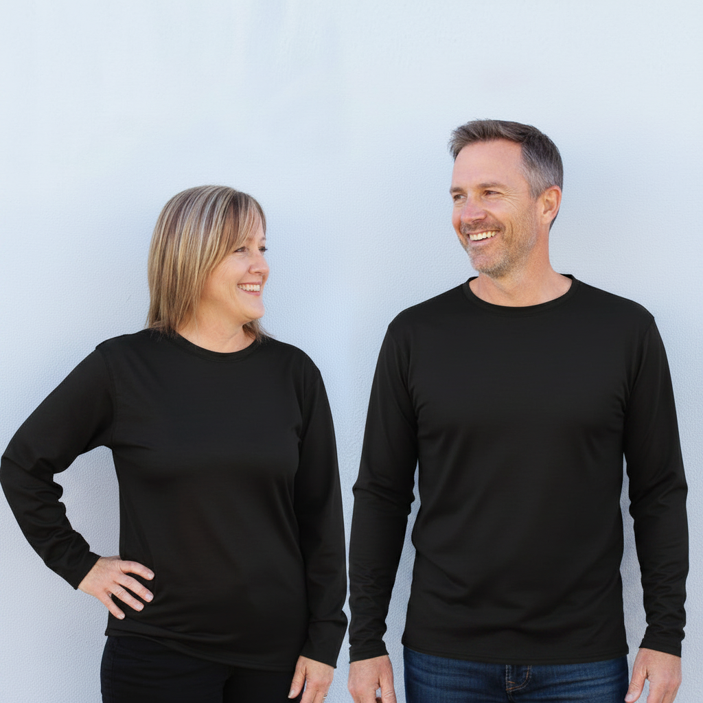 A man and a woman standing side by side, both wearing plain black long-sleeve crewneck shirts against a light gray studio background.
